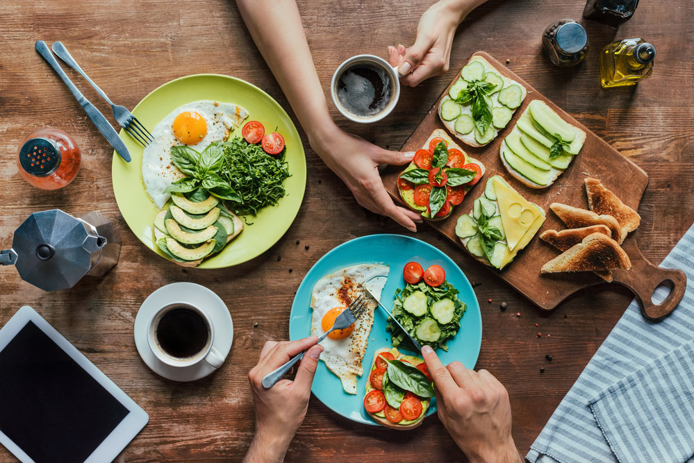 Übersicht: Frühstück mit Kaffee und belegtem Toast am Tisch zu zweit.