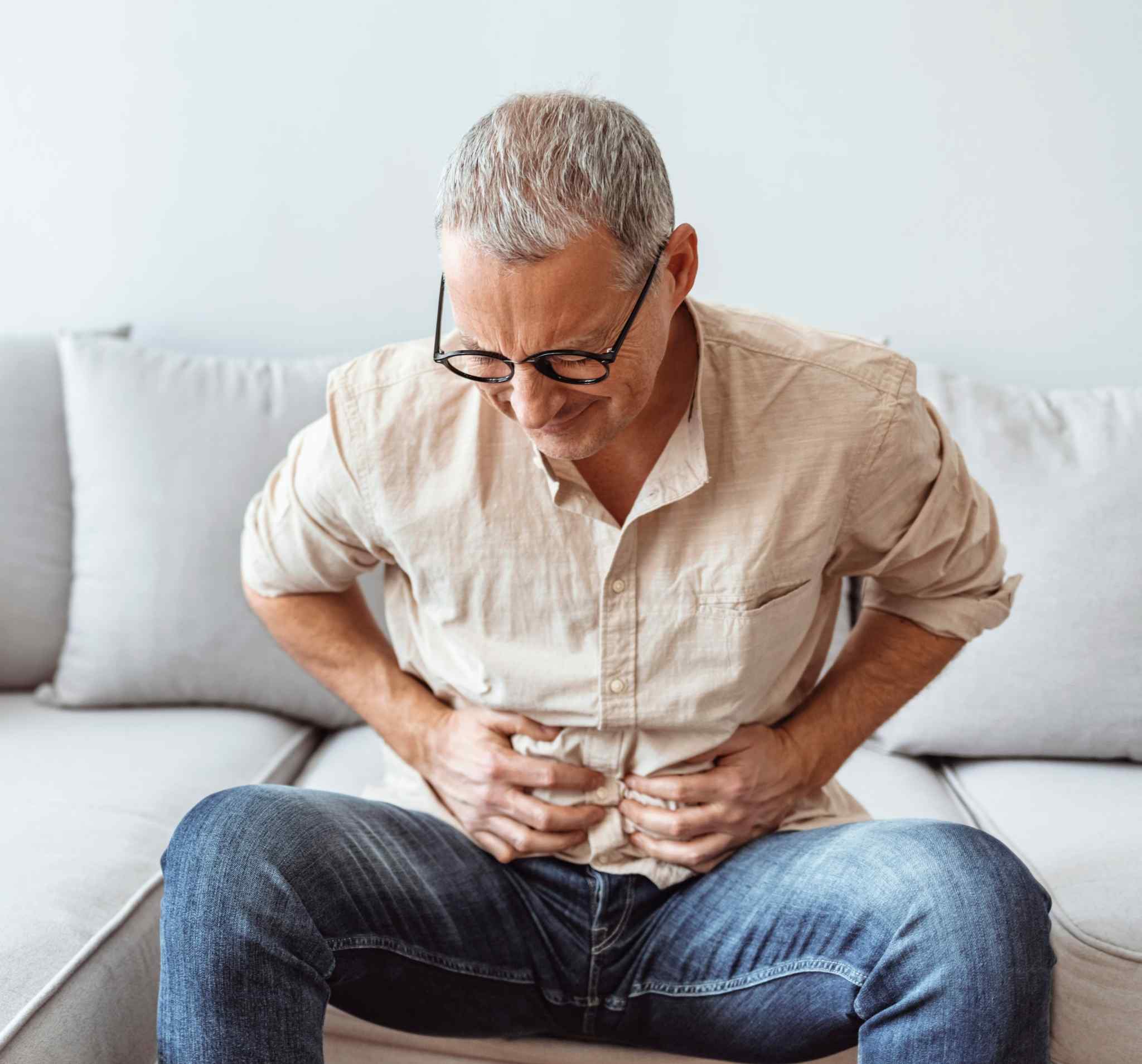 Mature man feeling unwell with a stomach ache while sitting at home