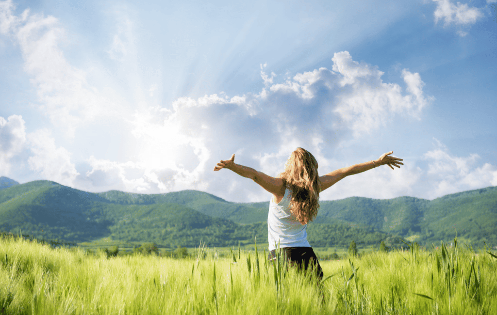 young woman with hands outstretched in the field